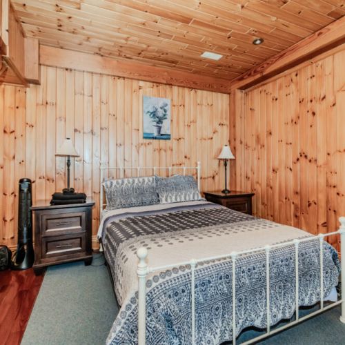 Inviting queen bedroom with cabin-style charm and soft bedding—ideal for restful nights after beach walks, kayaking, or hiking adventures.