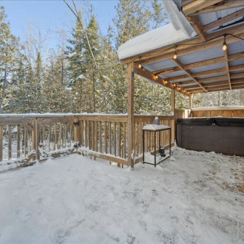 Private hot tub area with forest views and a cozy covered setup. A perfect spot to relax in the fresh air, surrounded by snow and trees.