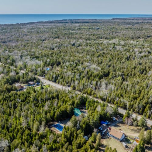 Scenic aerial view of a wooded coastal region with private properties—ideal for serene vacation rentals and nature-filled getaways.