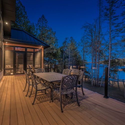 Unwind on the spacious deck of this lakefront vacation rental, featuring a stylish outdoor dining area and stunning views—ideal for al fresco dinners, stargazing, and relaxing getaways in nature.