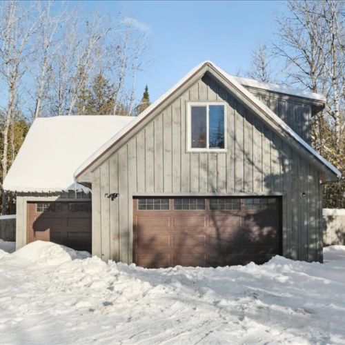 Exterior view of the loft suite above the heated garage, tucked into a private wooded setting. Cozy, quiet, and designed for a comfortable extended stay.