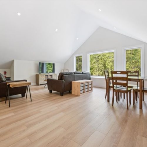 Spacious and sunlit, this upper-level loft offers flexible living with room to lounge, play, or dine — all framed by forest views through oversized windows.