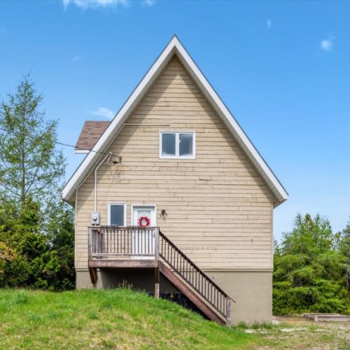 The front of the home features a cozy porch entry and classic triangular architecture, ideal for a serene cottage getaway.