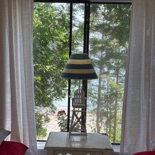 Striped lamp and lake views framed by airy curtains.