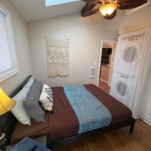 A bright bedroom featuring a calming design. A peaceful retreat ideal for couples or solo travellers seeking comfort and relaxation. Washer and dryer also in this bedroom