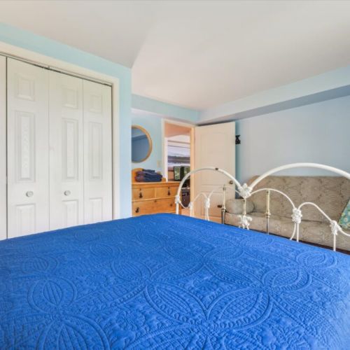 A wider view of the same bedroom highlights the wooden dresser, closet space, and cozy daybed tucked against the wall.