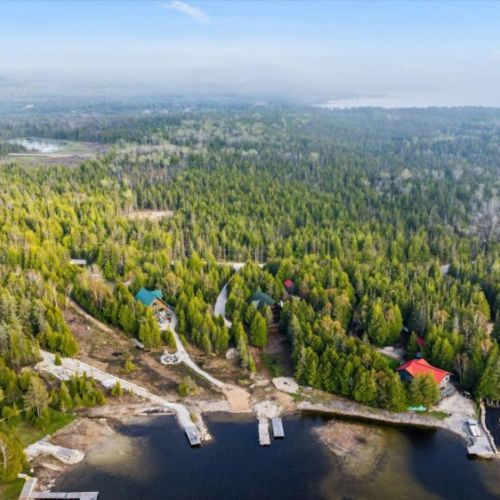 An aerial view of the property showcases the private shoreline, dock, and scenic surroundings.