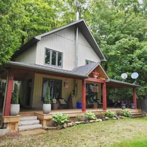 Exterior view of Porchlight & Pines surrounded by peaceful forest scenery.