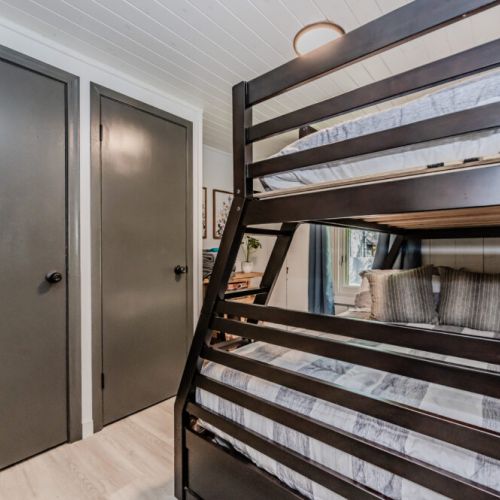 This cozy bedroom features a modern bunk bed with a double bed on the bottom and a single bed on top