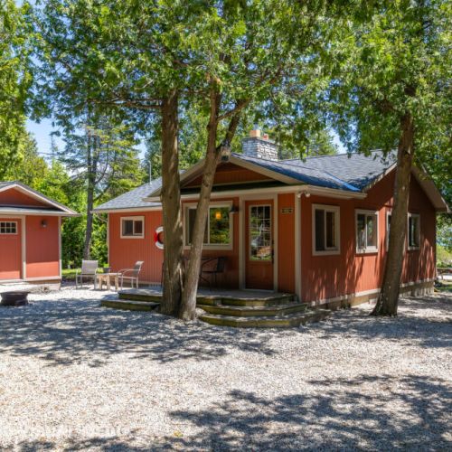 Bright lakeside cottage nestled under mature trees for shade and privacy.