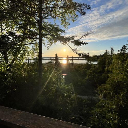 A stunning view from the property showcasing the beautiful sunset over the lush greenery and a glimpse of the lake in the background.