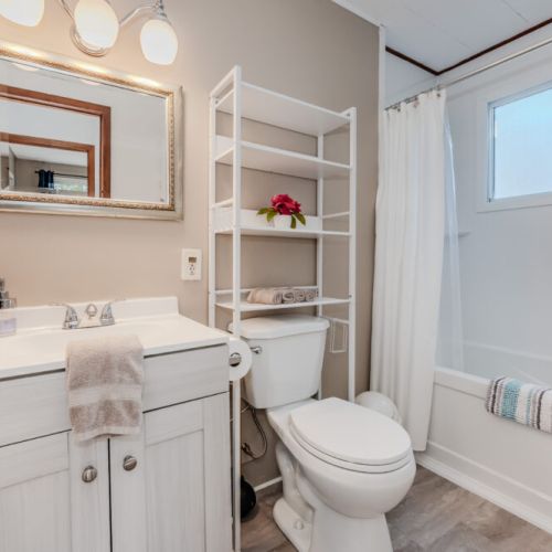 Modern bathroom with tub/shower combo, storage shelves, and elegant touches—clean, functional, and perfect for families or couples.