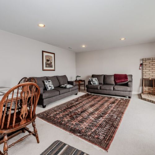 The lower-level family room invites you to relax with its cozy seating, large windows, and wood-burning stove for those cooler nights.