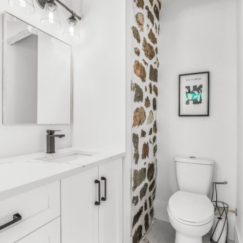 Bright powder room with a clean modern vanity and charming stone accent wall.