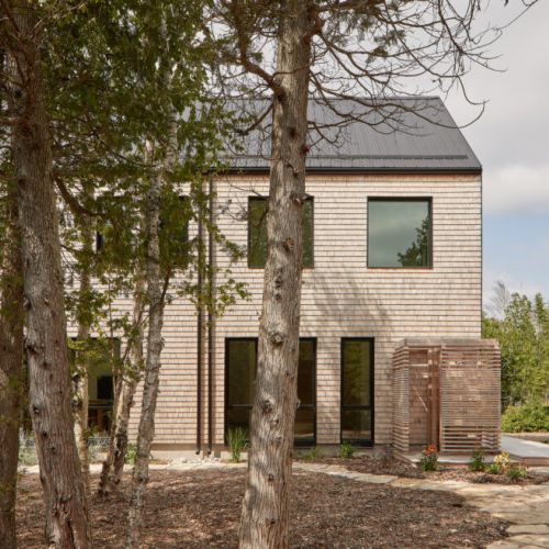 A beautiful backyard with outdoor shower and a stone path leading through the trees, enhancing the cottage’s connection to nature.