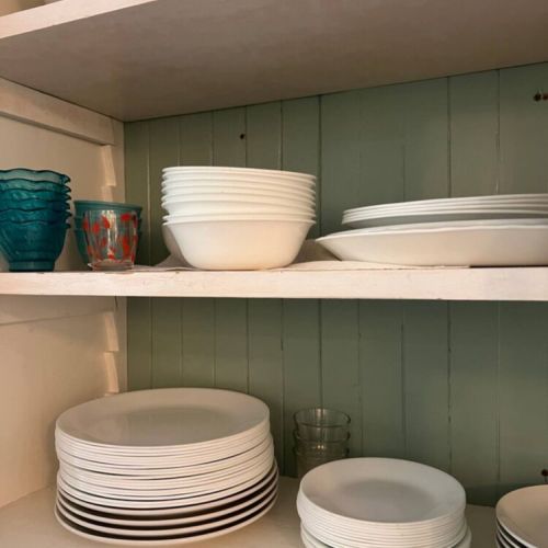 A thoughtfully stocked kitchen with everything you need — from crisp white dinnerware to wine glasses and mugs — ready for shared meals and cozy nights in.