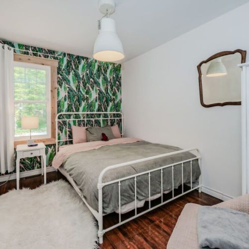 Chic and cozy guest room with a queen bed, hotel-quality linens, and leafy forest views. Comfort and style for a restful night’s sleep.