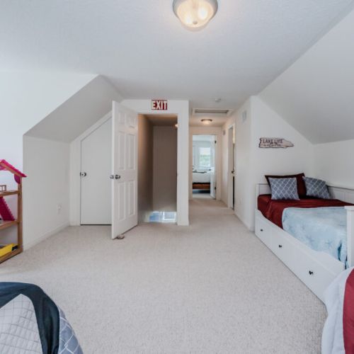 The guest bedroom has plenty of natural light, offering a cozy corner for dreams and play with a dollhouse and toys by the window, great for families.