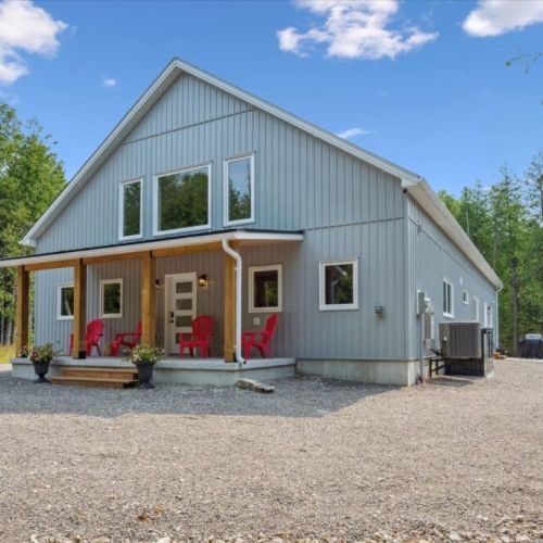 Modern charm in a forested setting — this spacious cottage features clean lines, vaulted ceilings, and a cozy front porch perfect for morning coffee or evening chats.