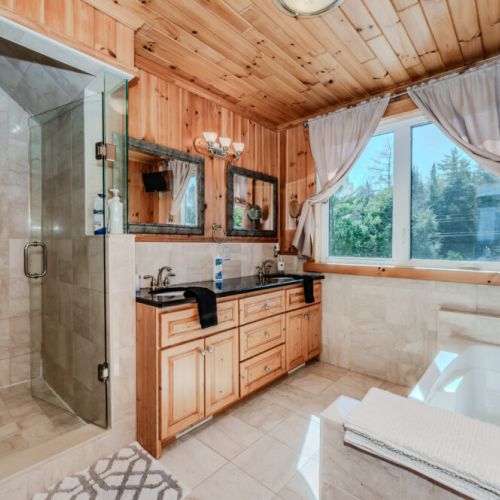 Spacious ensuite with double vanity, glass shower, and soaker tub—your private spa retreat during a luxury cabin getaway.