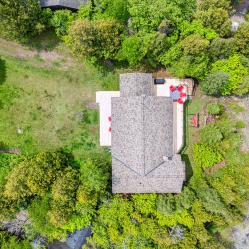 This top-down shot shows off the cottage’s generous lawn, wraparound decks, shoreline firepit, and natural privacy all around.