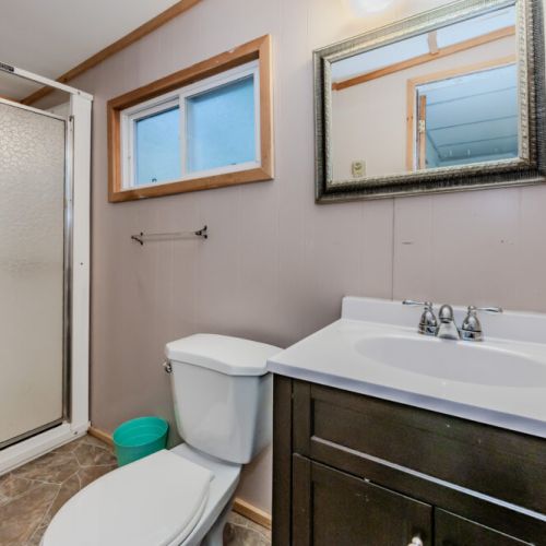 The bathroom in the Oahu cabin offers a spacious shower, modern sink, and vanity with ample counter space. A well-lit mirror and fresh décor provide a comfortable and convenient space for your daily routines.