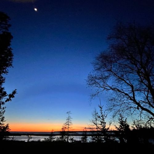 Twilight descends at Silver Birch Cottage, with the horizon glowing in vivid orange as the day fades into night.