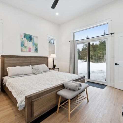 Bright bedroom with patio access offering forest views and seamless indoor-outdoor flow.