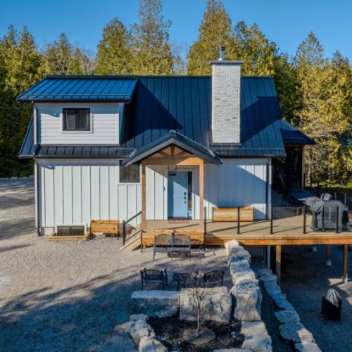 Modern cottage retreat surrounded by forest with a spacious deck and BBQ area. Ideal for nature lovers, outdoor dining, and peaceful vacation stays near the lake.