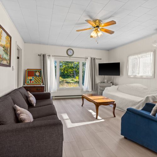 Bright and comfortable living room with plenty of seating, a flat-screen TV and large windows overlooking the peaceful property.
