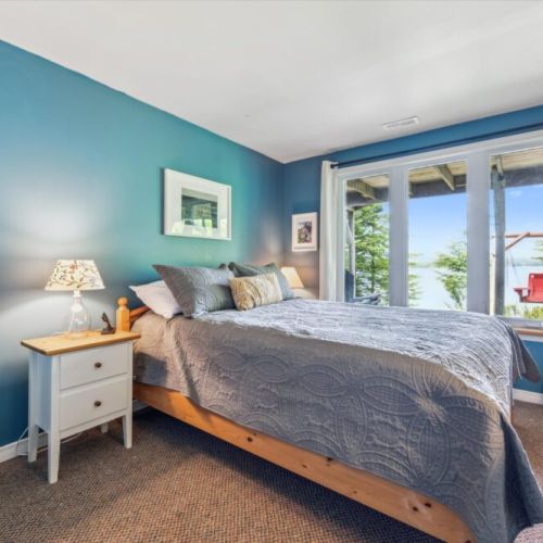 Drift off to the sound of the breeze in this teal-toned bedroom, where the large windows frame stunning water views and natural light floods the space.
