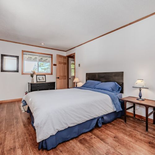 Spacious bedroom with large windows and natural light, perfect for a peaceful night’s sleep during your relaxing cottage stay.