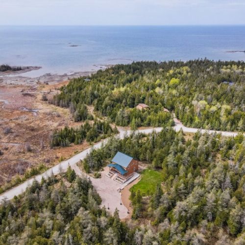 An aerial view captures the cabin's secluded location amidst lush greenery, offering breathtaking vistas of the surrounding landscape and waters.