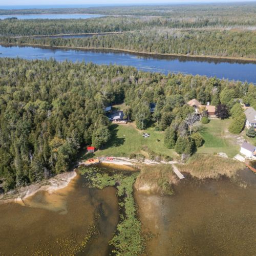 Aerial view showing Midnight Star tucked into the trees with a wide waterfront lawn.