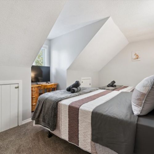 Charming loft bedroom tucked beneath the cottage roofline, creating a cozy and relaxing getaway space.