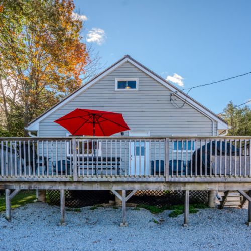 A spacious deck complete with a red umbrella, providing shade for outdoor dining and relaxation.