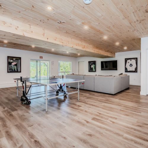 Another angle of the recreation room, showing more of the decor and layout. The room is bright and inviting, with large windows and doors that open to the outdoor area.