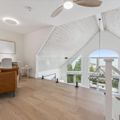 A bright upper-level nook with a desk and lounge chair, ideal for working remotely or relaxing with a view of the lake.