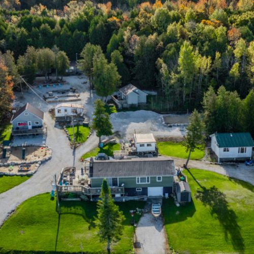 Welcome to Bayshore Cottages with  an aerial view of the property, showing the close-knit arrangement of cottages with communal areas and playgrounds.