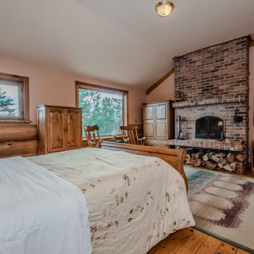 Cozy up in this charming bedroom featuring a brick fireplace, vaulted ceiling, and tranquil views. The perfect blend of comfort and rustic charm ensures a restful stay.