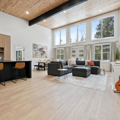 Open-concept living space with soaring wood ceilings, large windows, cozy seating, and room to relax or entertain.