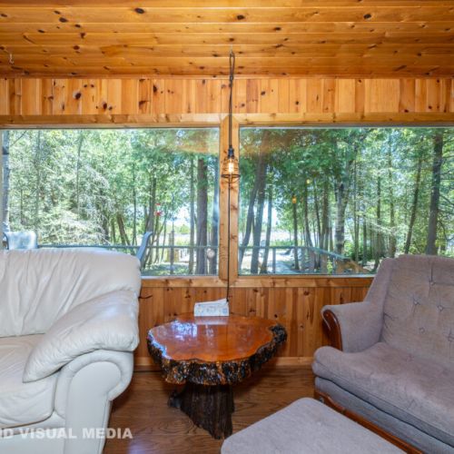 Relax in the cozy lakeside living room, featuring huge picture windows that frame peaceful forest and waterfront views.