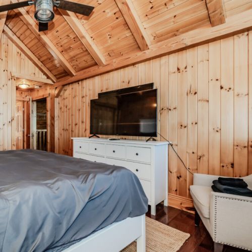 Elegant master suite with cathedral ceilings, large TV, and lounge chair—relax in comfort after days spent exploring or unwinding lakeside.