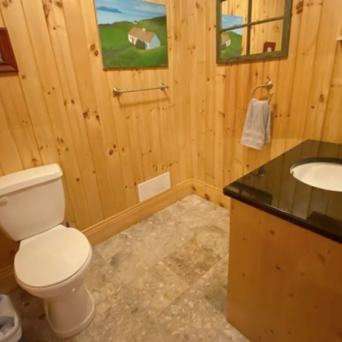 This charming powder room combines functionality with rustic style, featuring natural wood walls and a sleek granite countertop.