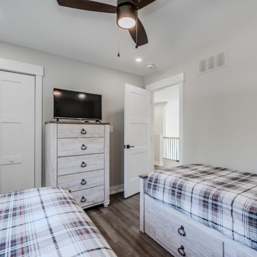 Another view of the twin bedroom, showcasing the dresser and TV. The room is designed for comfort and is perfect for kids and extra guests.