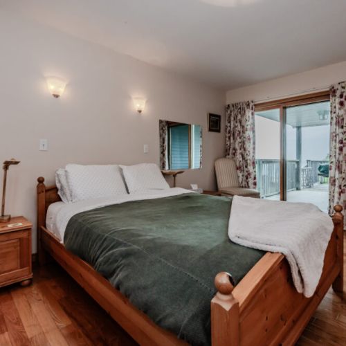 Primary bedroom with cozy bedding, soft lighting, and a peaceful view—ideal for unwinding after a day at the beach or on the trails.