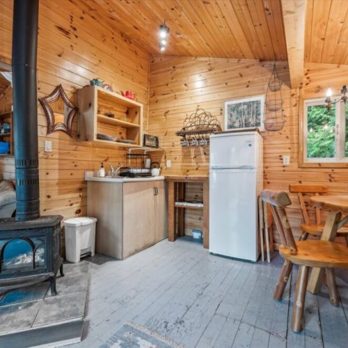 A charming galley-style kitchen is fully equipped for simple cottage meals. Nearby, the wood-burning stove offers both warmth and ambiance for those cooler evenings in the woods.