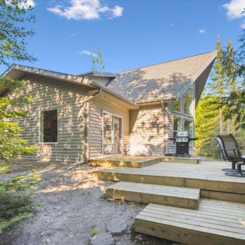 Spacious wooden deck offering multiple seating areas and a natural transition between indoors and the forest surroundings.