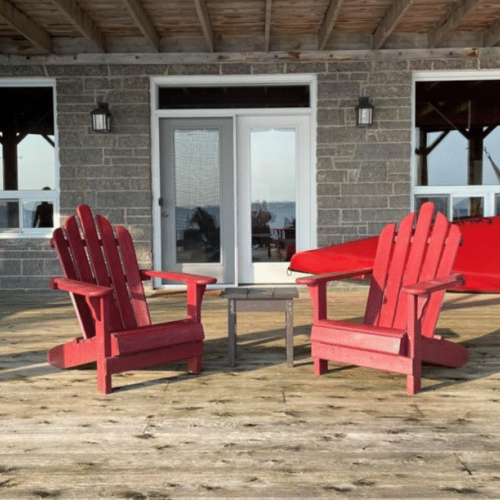 Relax in vibrant red Adirondack chairs on the spacious deck, with easy access to water activities and beautiful surroundings.