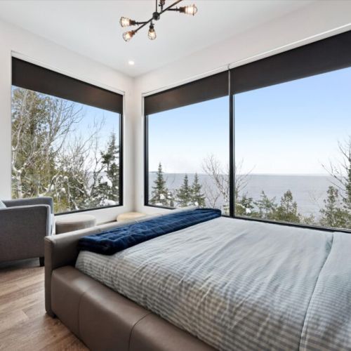 Wake up to treetop and Georgian Bay views in a light-filled bedroom designed for rest, comfort, and quiet mornings.